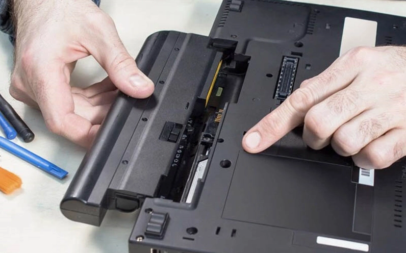Thao tác gạt lẫy khóa an toàn để tháo viên pin rời nằm ở mặt lưng của laptop Acer trước khi mở máy