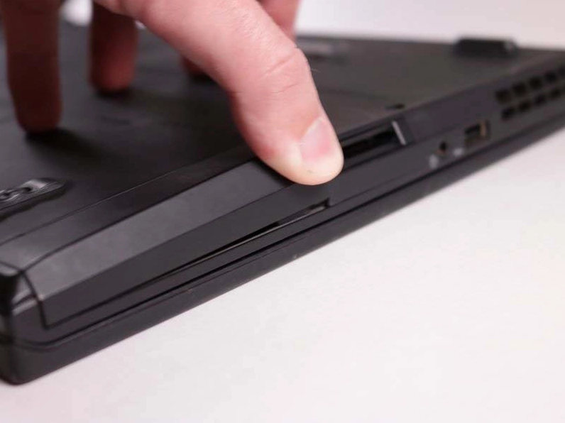 Thao tác vặn mở ốc cố định nắp che khu vực chứa ổ cứng trên máy Lenovo