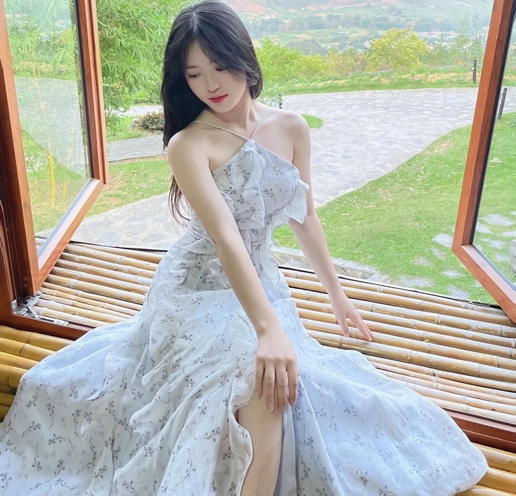 Vàng Thị Sinh diện đầm maxi hai dây tạo dáng bên khung cửa sổ