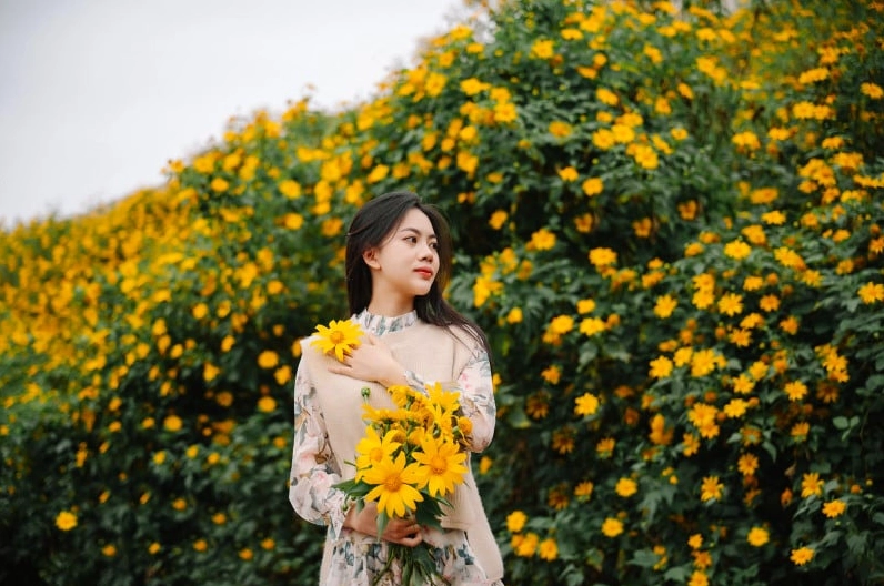 Ảnh cô gái cầm hoa đẹp giữa không gian xanh mướt